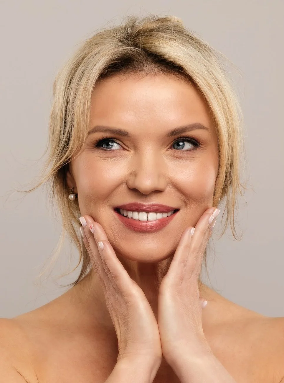 Smiling woman with smooth, bright under-eye skin, hands framing her face